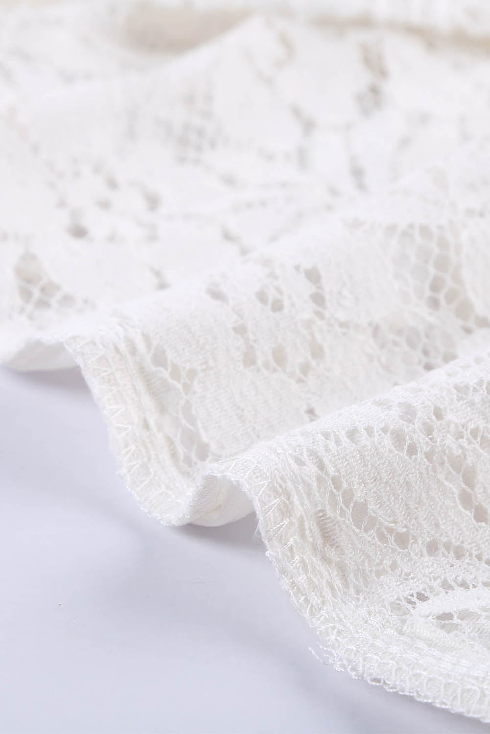 A stylish white lace v neck tank top featuring a delicate floral lace design, sleeveless cut, and a daring hollow-out back.