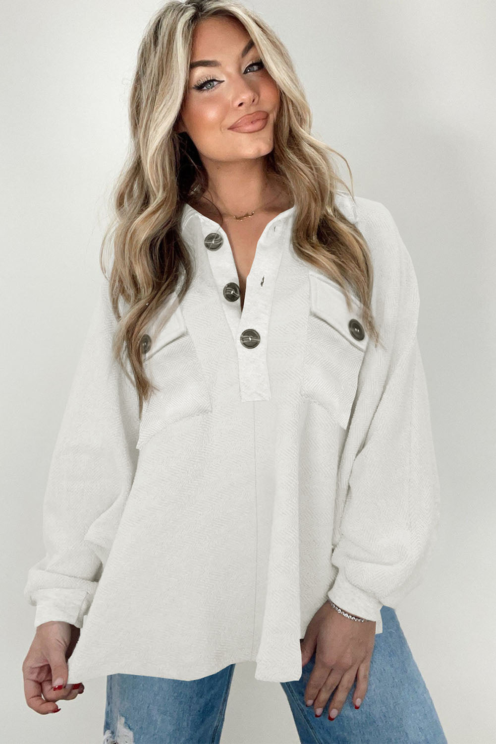 A stylish white oversized sweatshirt featuring flap pockets, a button collared neck, and loose sleeves, perfect for casual wear.