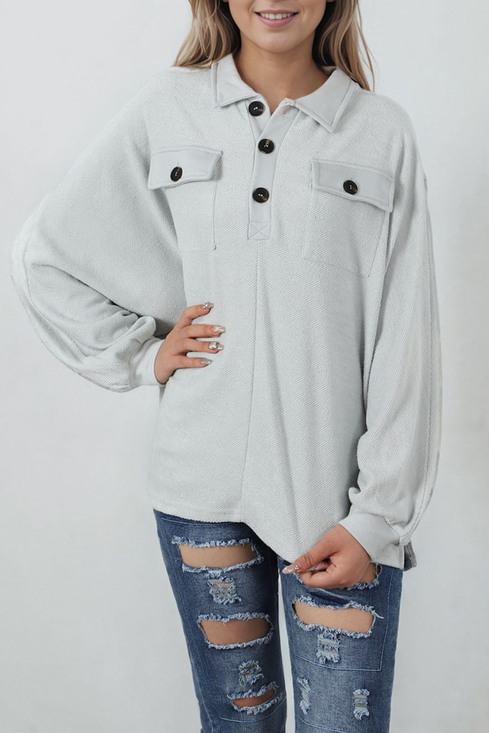 A stylish white oversized sweatshirt featuring flap pockets, a button collared neck, and loose sleeves, perfect for casual wear.