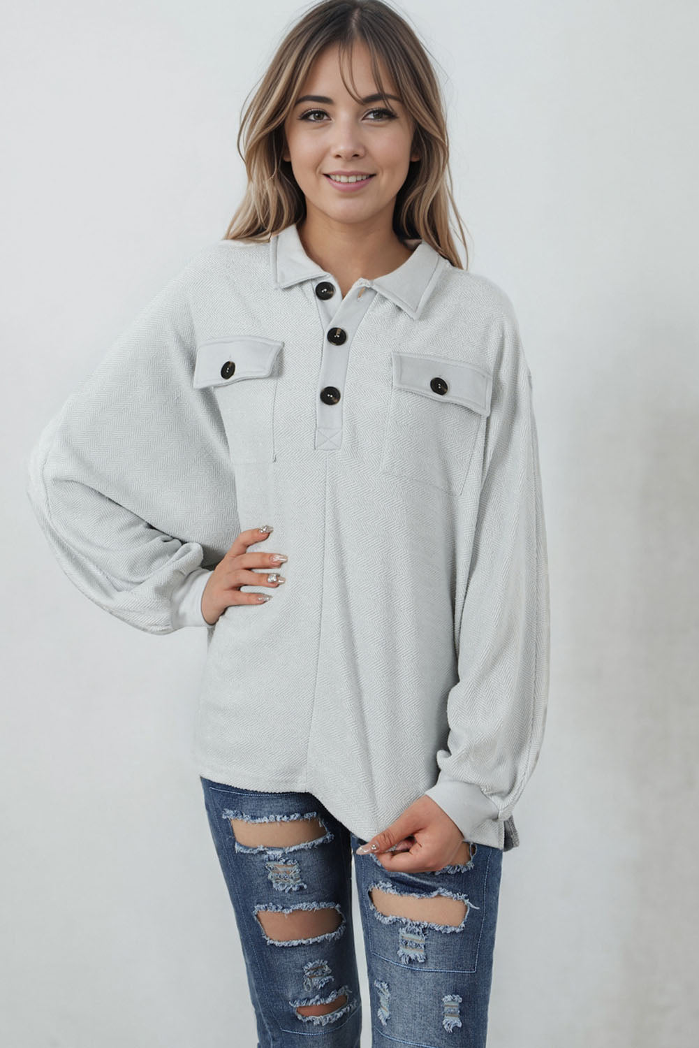 A stylish white oversized sweatshirt featuring flap pockets, a button collared neck, and loose sleeves, perfect for casual wear.