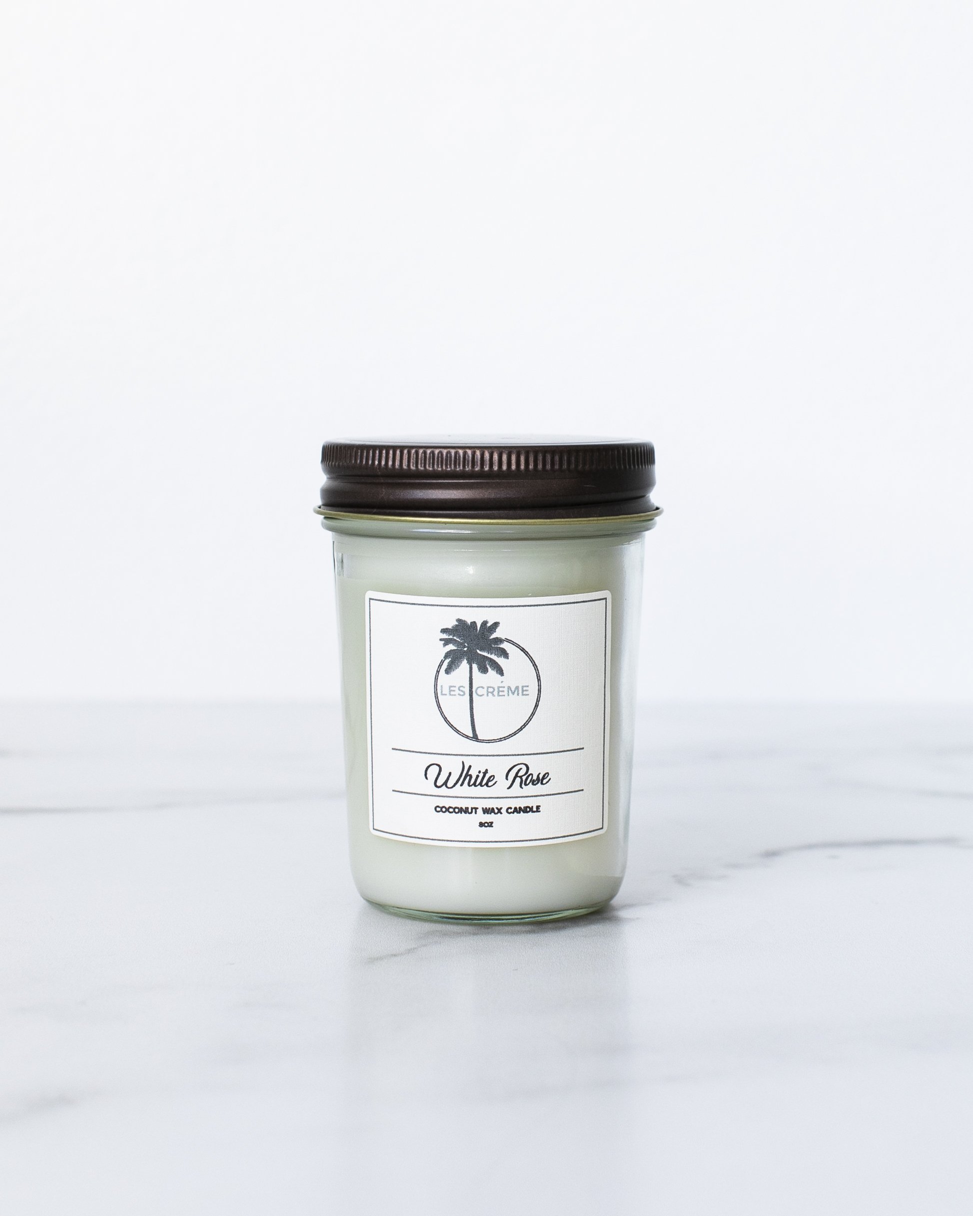 A beautifully crafted White Rose Scent Coconut Wax Candle in a glass jar, showcasing its elegant design and natural ingredients.