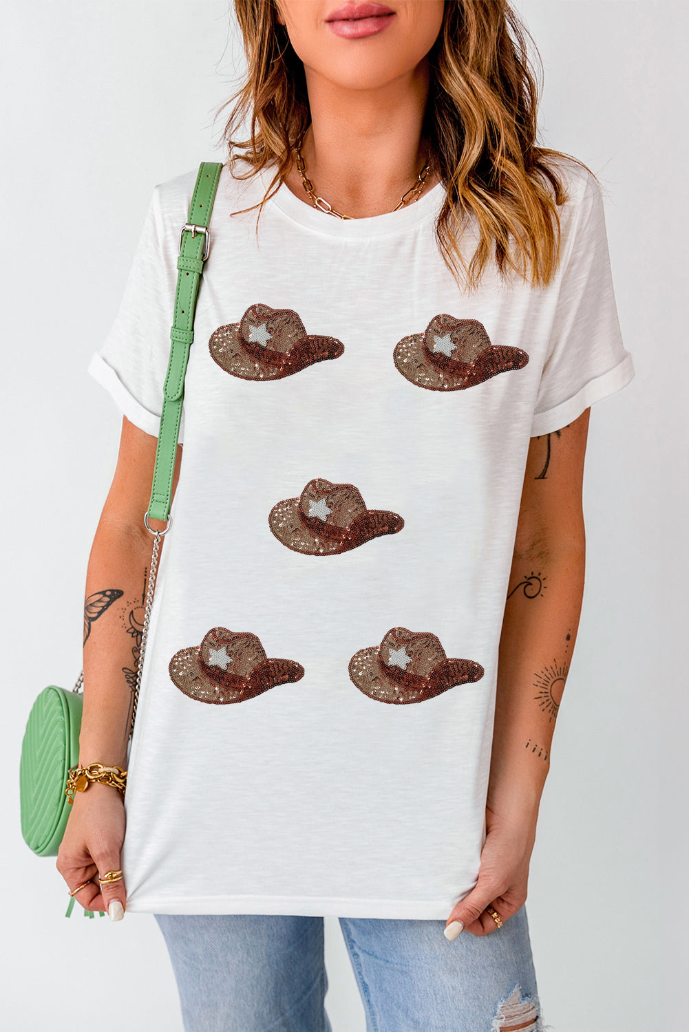 White t-shirt featuring a graphic of cowgirl hats embellished with sequins, perfect for casual wear.