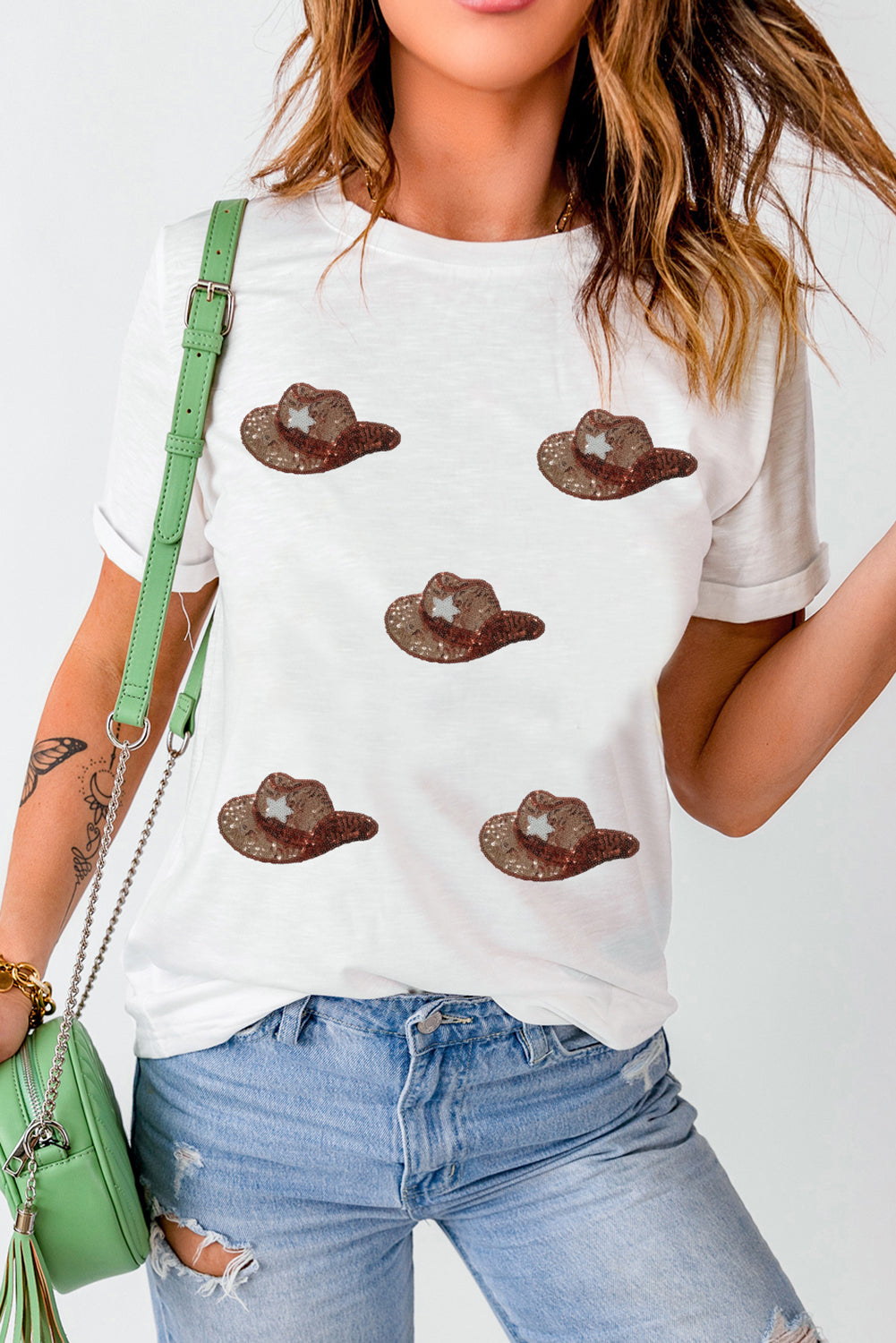 White t-shirt featuring a graphic of cowgirl hats embellished with sequins, perfect for casual wear.