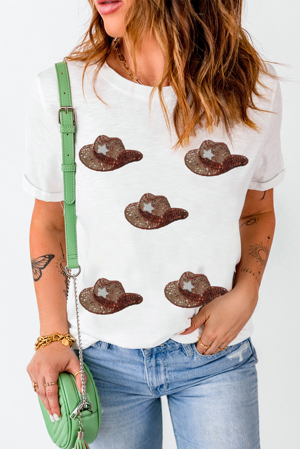 White t-shirt featuring a graphic of cowgirl hats embellished with sequins, perfect for casual wear.