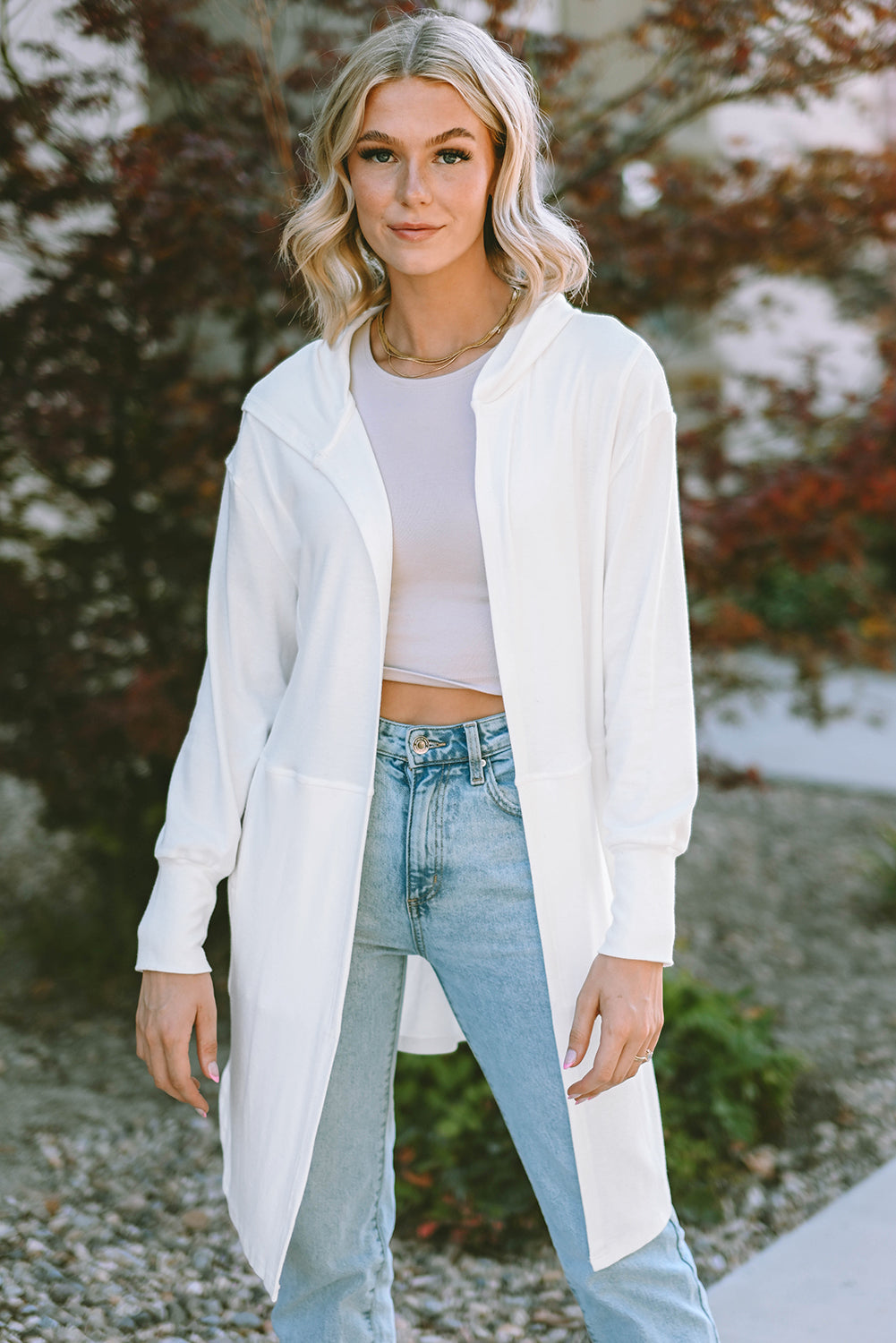 A stylish white hooded cardigan with side splits, featuring two pockets and a long design, perfect for modern women's fashion.