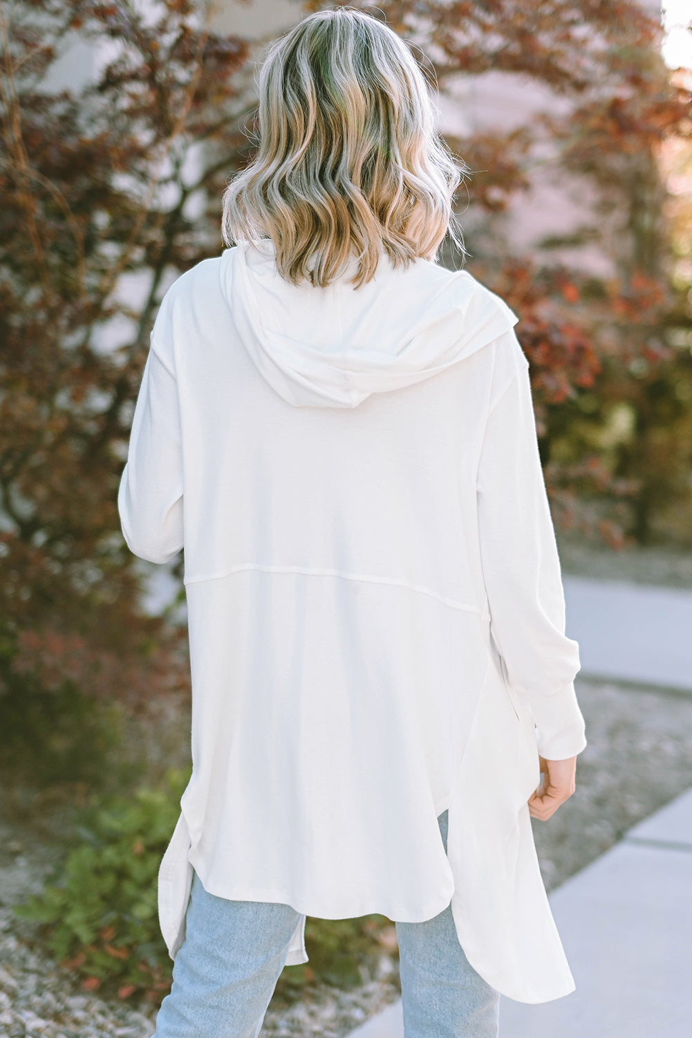 A stylish white hooded cardigan with side splits, featuring two pockets and a long design, perfect for modern women's fashion.