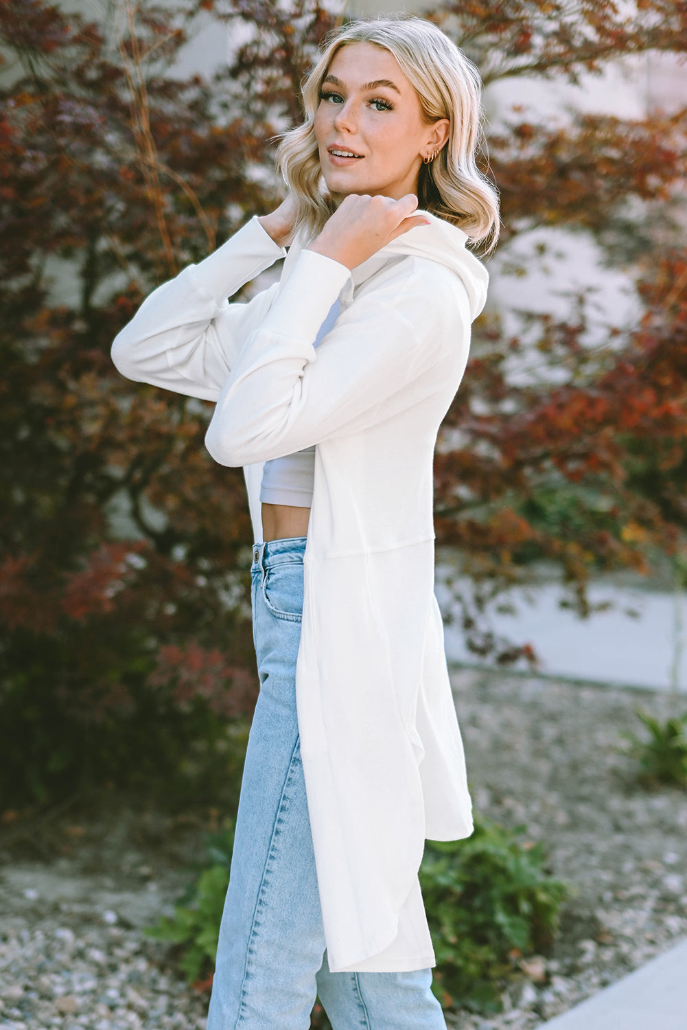 A stylish white hooded cardigan with side splits, featuring two pockets and a long design, perfect for modern women's fashion.