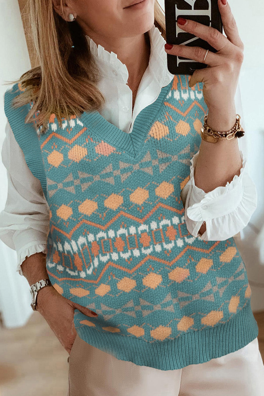 A stylish white knitted sweater vest featuring a unique tribal print design, perfect for layering during colder months.