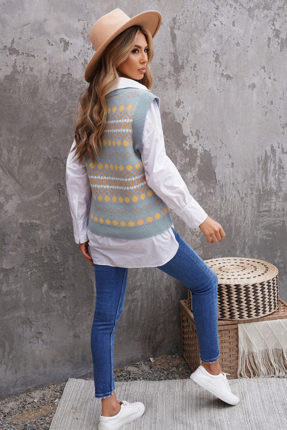 A stylish white knitted sweater vest featuring a unique tribal print design, perfect for layering during colder months.