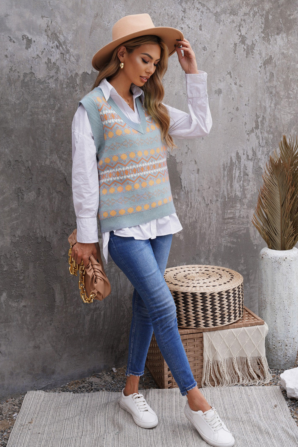 A stylish white knitted sweater vest featuring a unique tribal print design, perfect for layering during colder months.