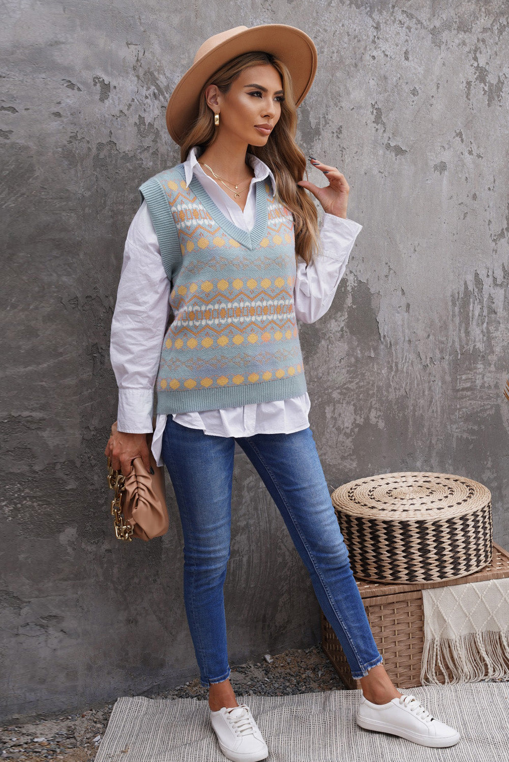 A stylish white knitted sweater vest featuring a unique tribal print design, perfect for layering during colder months.