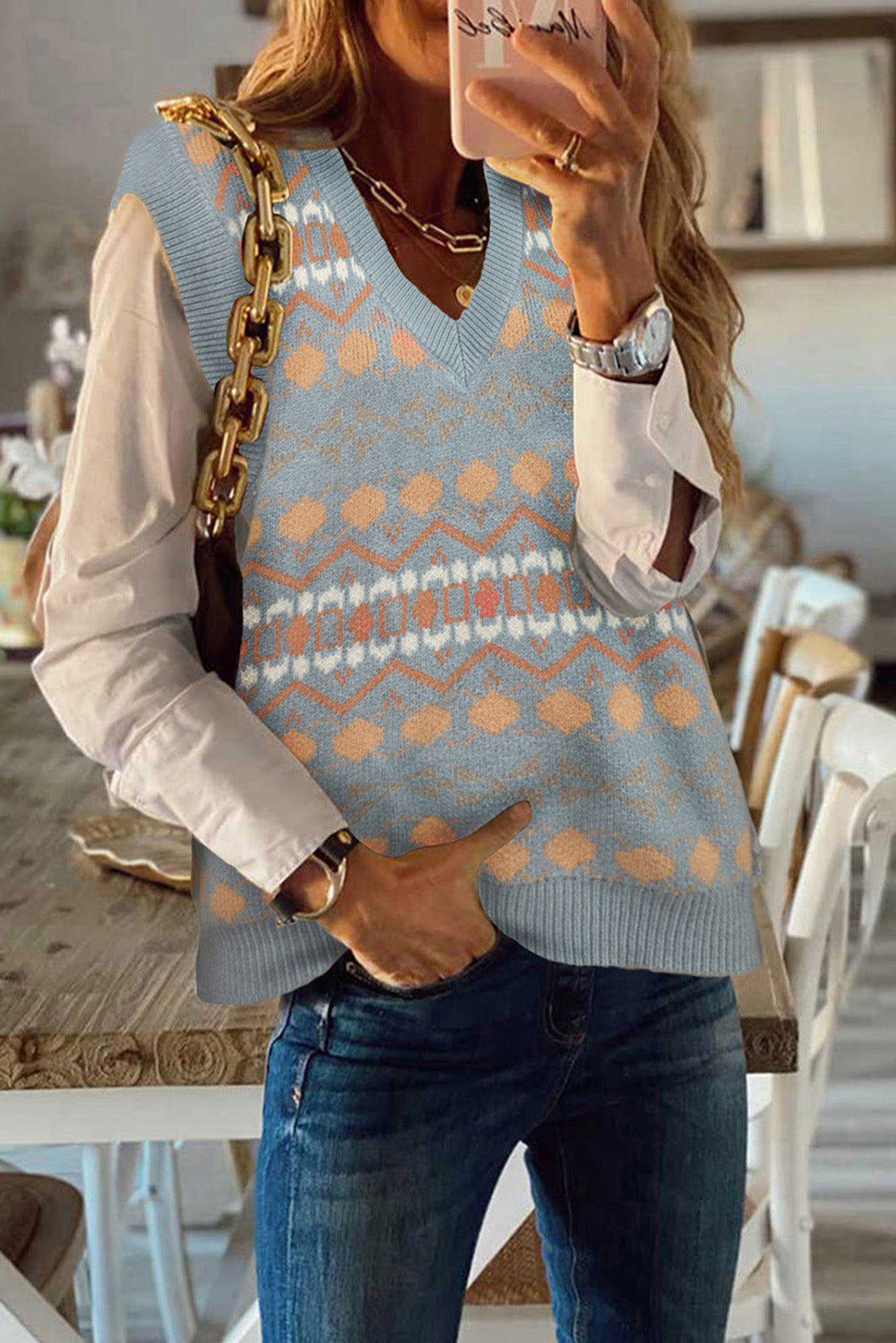 A stylish white knitted sweater vest featuring a unique tribal print design, perfect for layering during colder months.