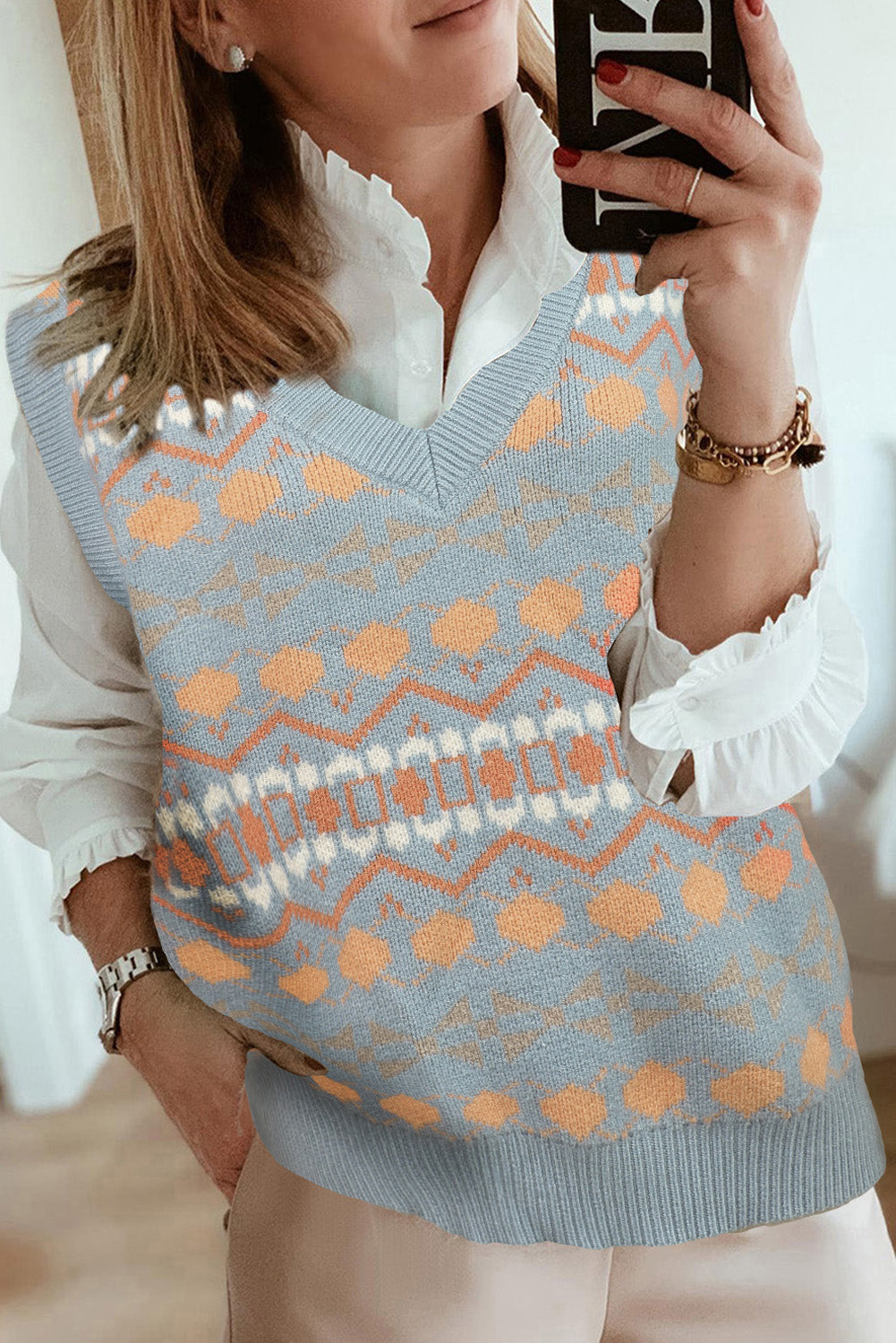 A stylish white knitted sweater vest featuring a unique tribal print design, perfect for layering during colder months.