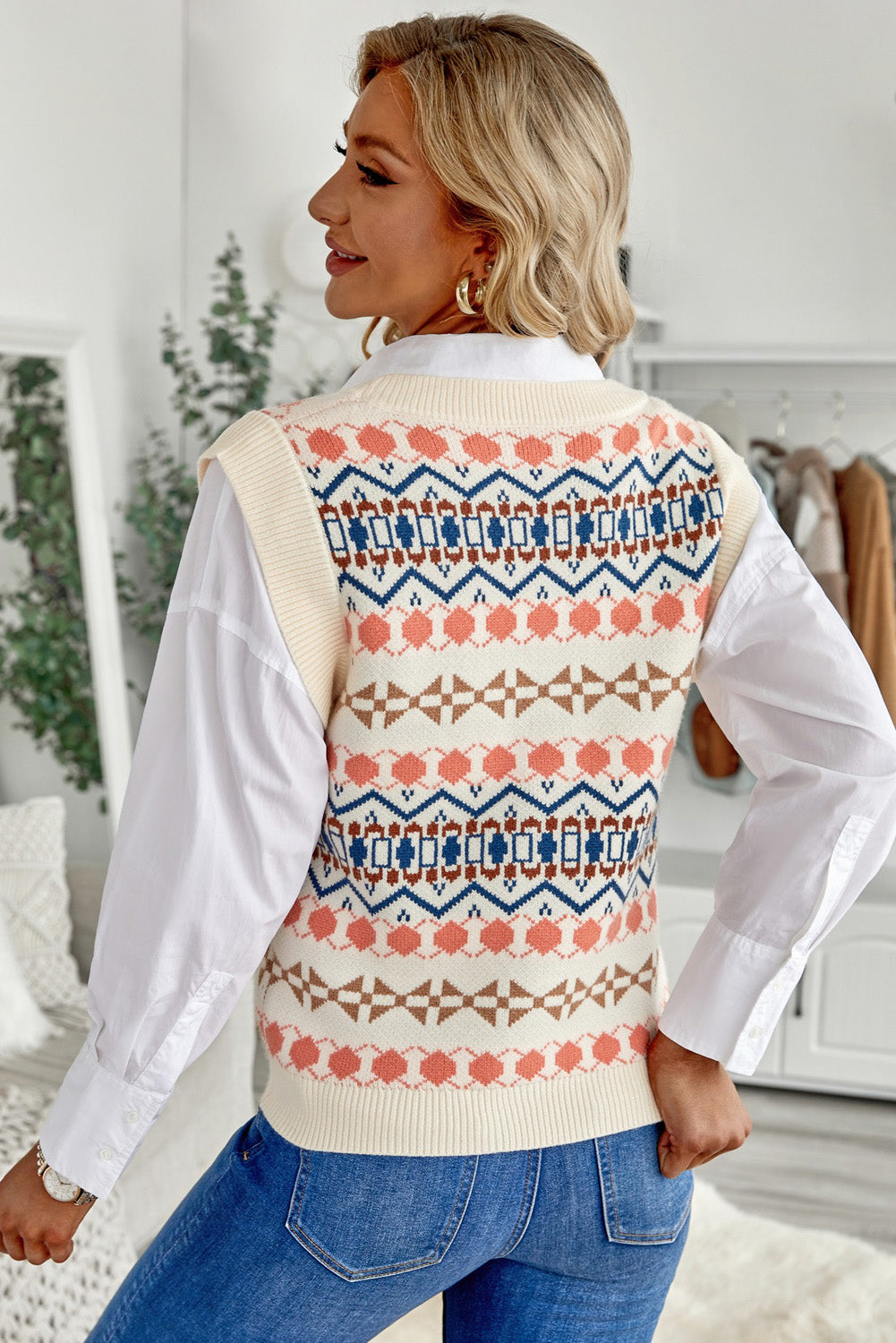 A stylish white knitted sweater vest featuring a unique tribal print design, perfect for layering during colder months.