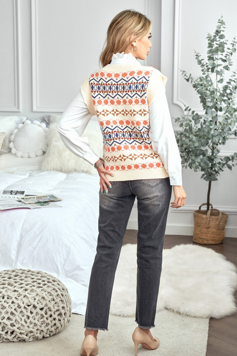 A stylish white knitted sweater vest featuring a unique tribal print design, perfect for layering during colder months.