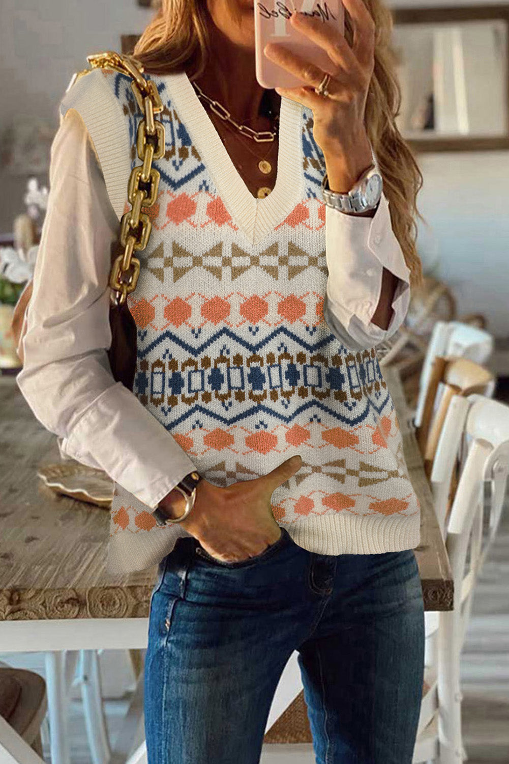 A stylish white knitted sweater vest featuring a unique tribal print design, perfect for layering during colder months.