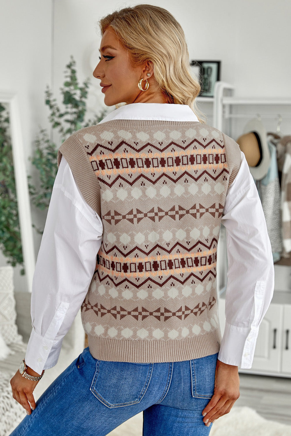 A stylish white knitted sweater vest featuring a unique tribal print design, perfect for layering during colder months.