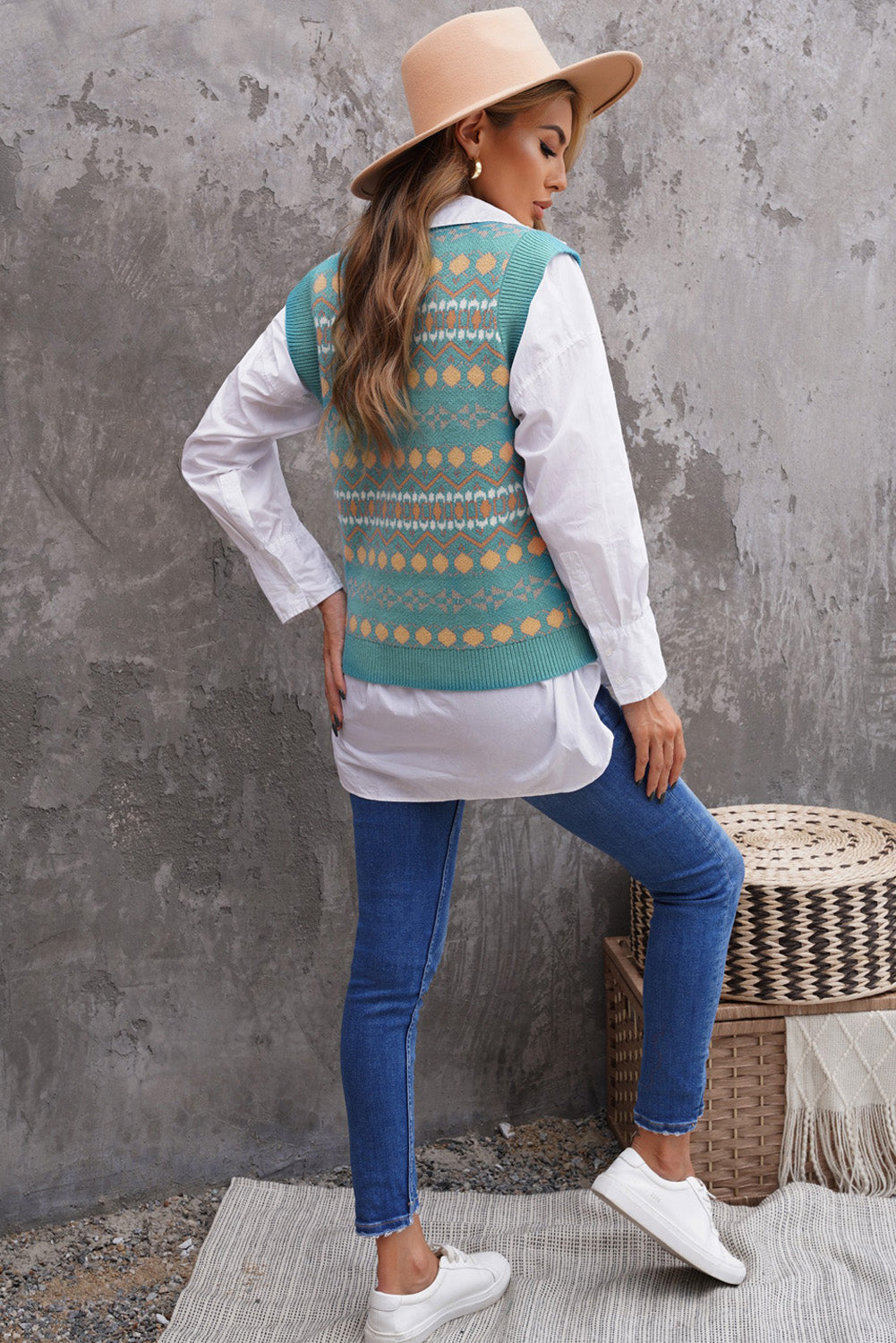 A stylish white knitted sweater vest featuring a unique tribal print design, perfect for layering during colder months.