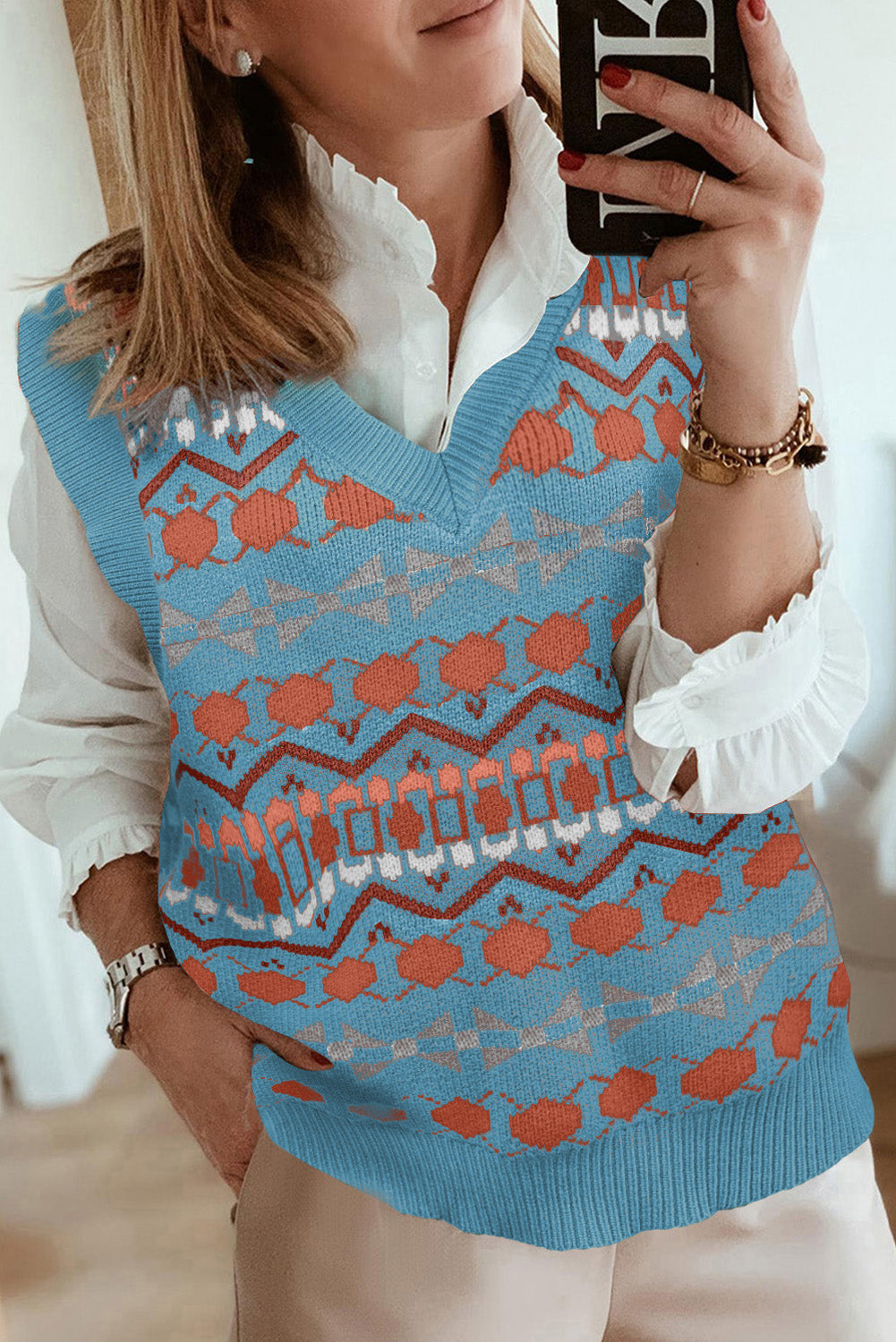 A stylish white knitted sweater vest featuring a unique tribal print design, perfect for layering during colder months.