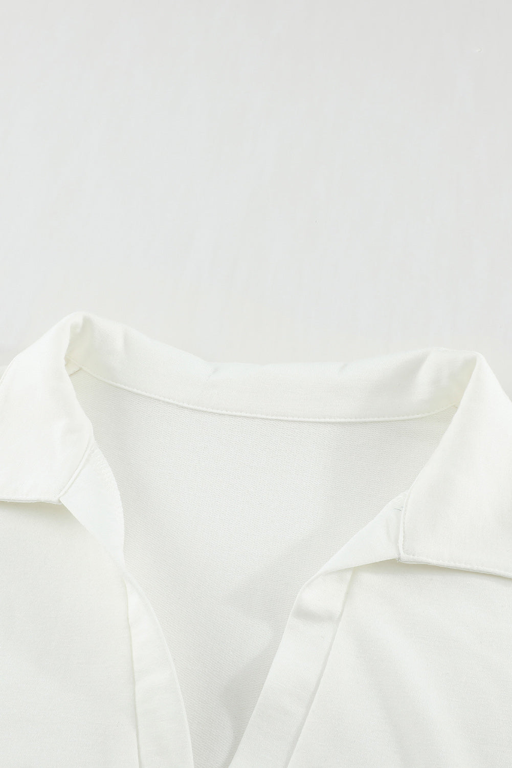 A stylish white turn-down V neck long sleeve top displayed on a mannequin, showcasing its elegant design and comfortable fabric.