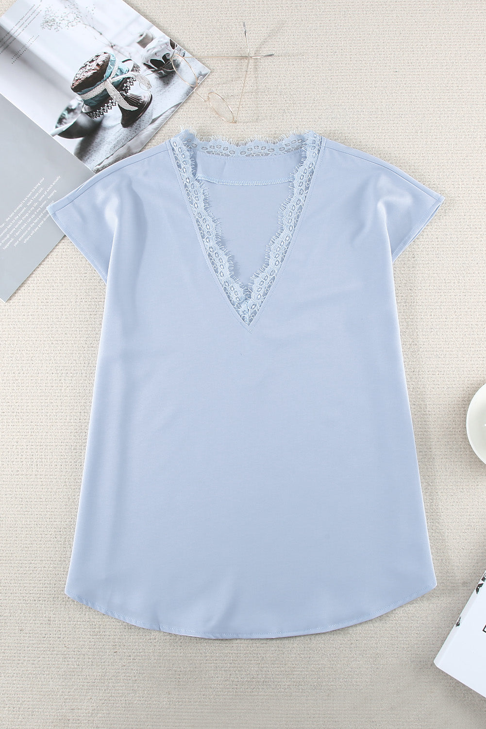 A stylish white V neck t-shirt featuring a delicate lace trim, showcasing its relaxed fit and elegant design.