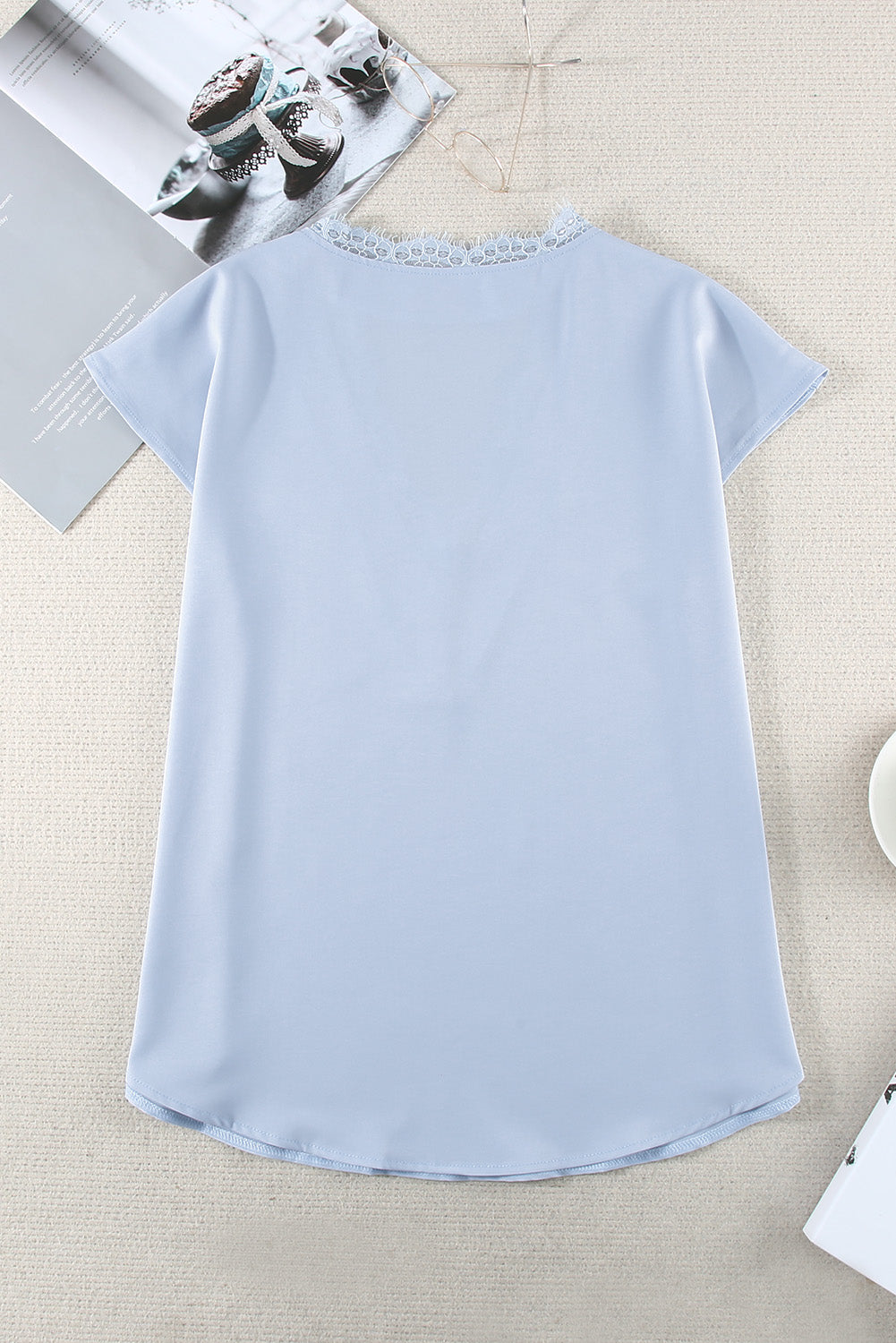 A stylish white V neck t-shirt featuring a delicate lace trim, showcasing its relaxed fit and elegant design.