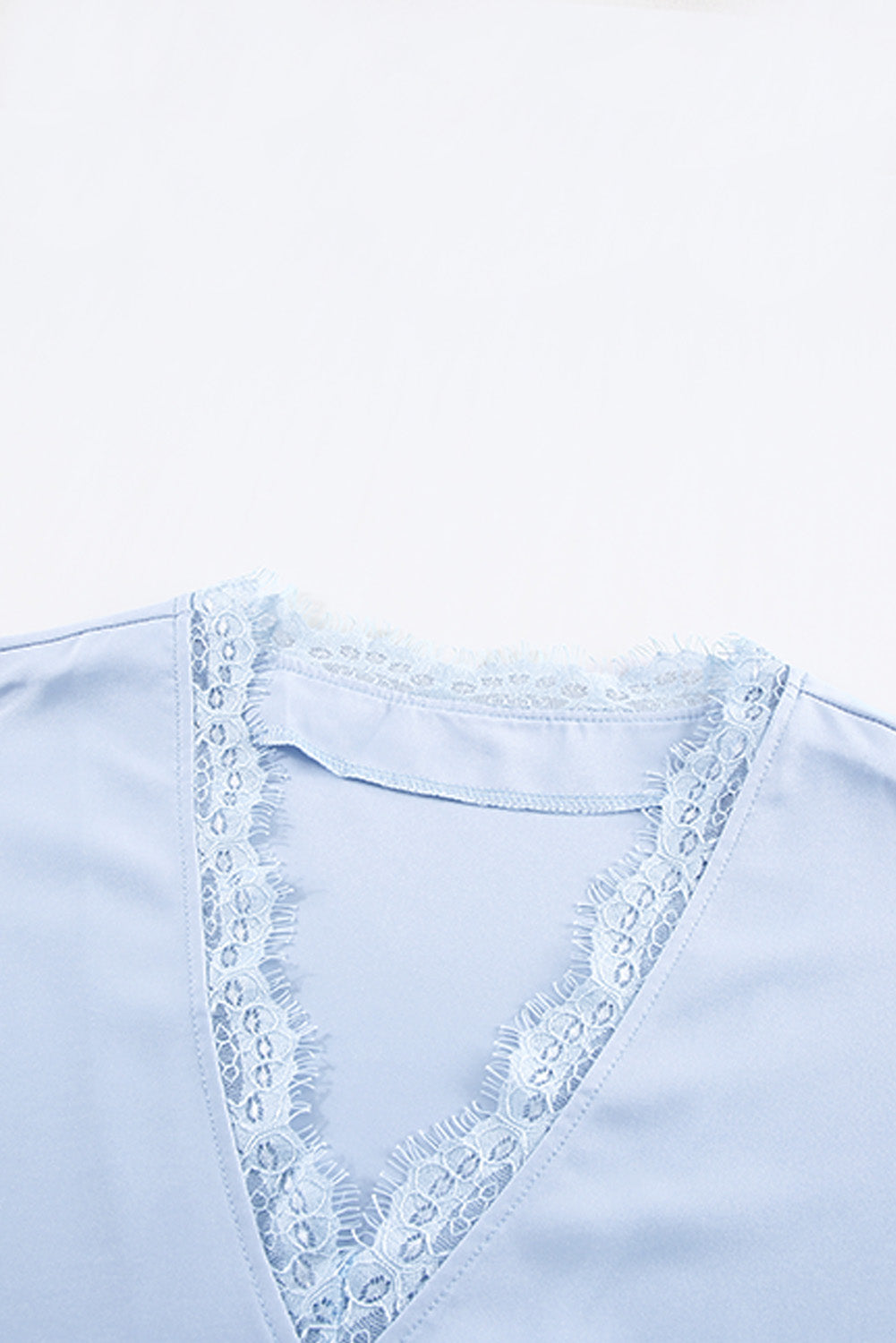 A stylish white V neck t-shirt featuring a delicate lace trim, showcasing its relaxed fit and elegant design.