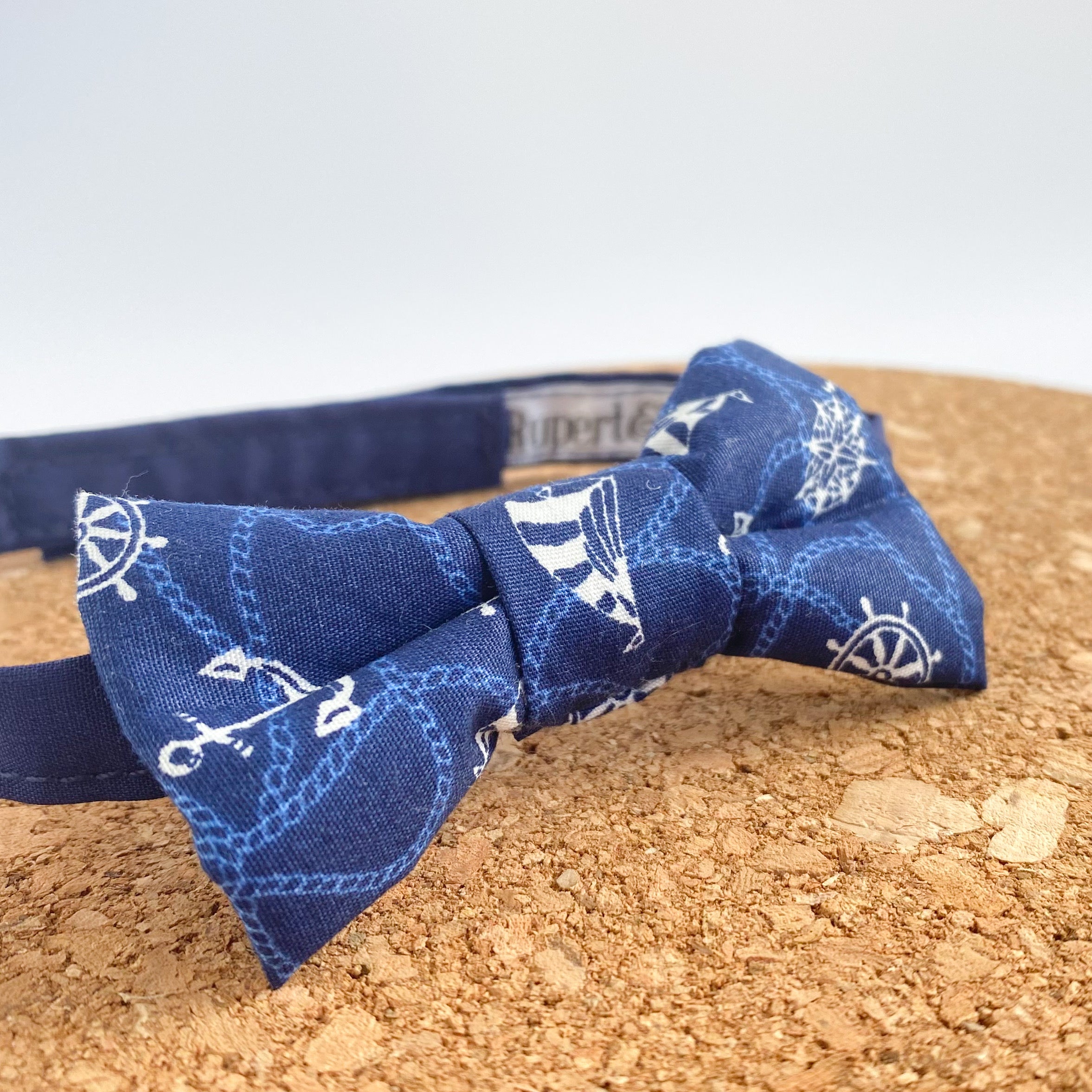 ERNEST Boys Bow Tie small in navy cotton with white nautical patterns, featuring sailing boats and anchors, perfect for young adventurers.