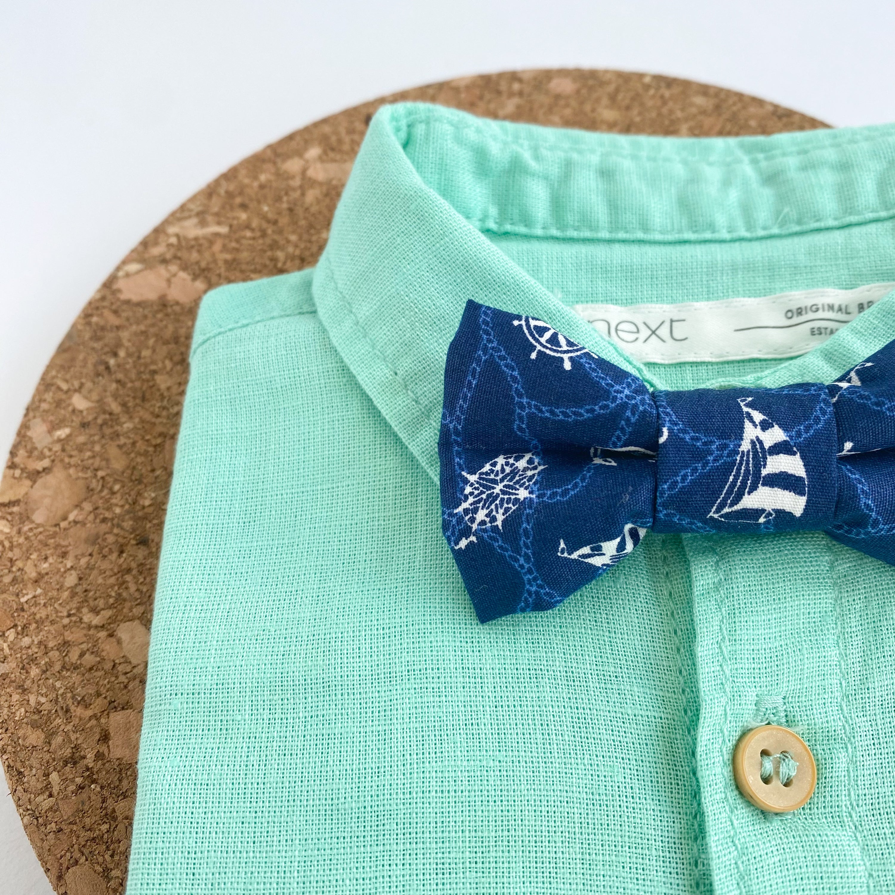 ERNEST Boys Bow Tie small in navy cotton with white nautical patterns, featuring sailing boats and anchors, perfect for young adventurers.