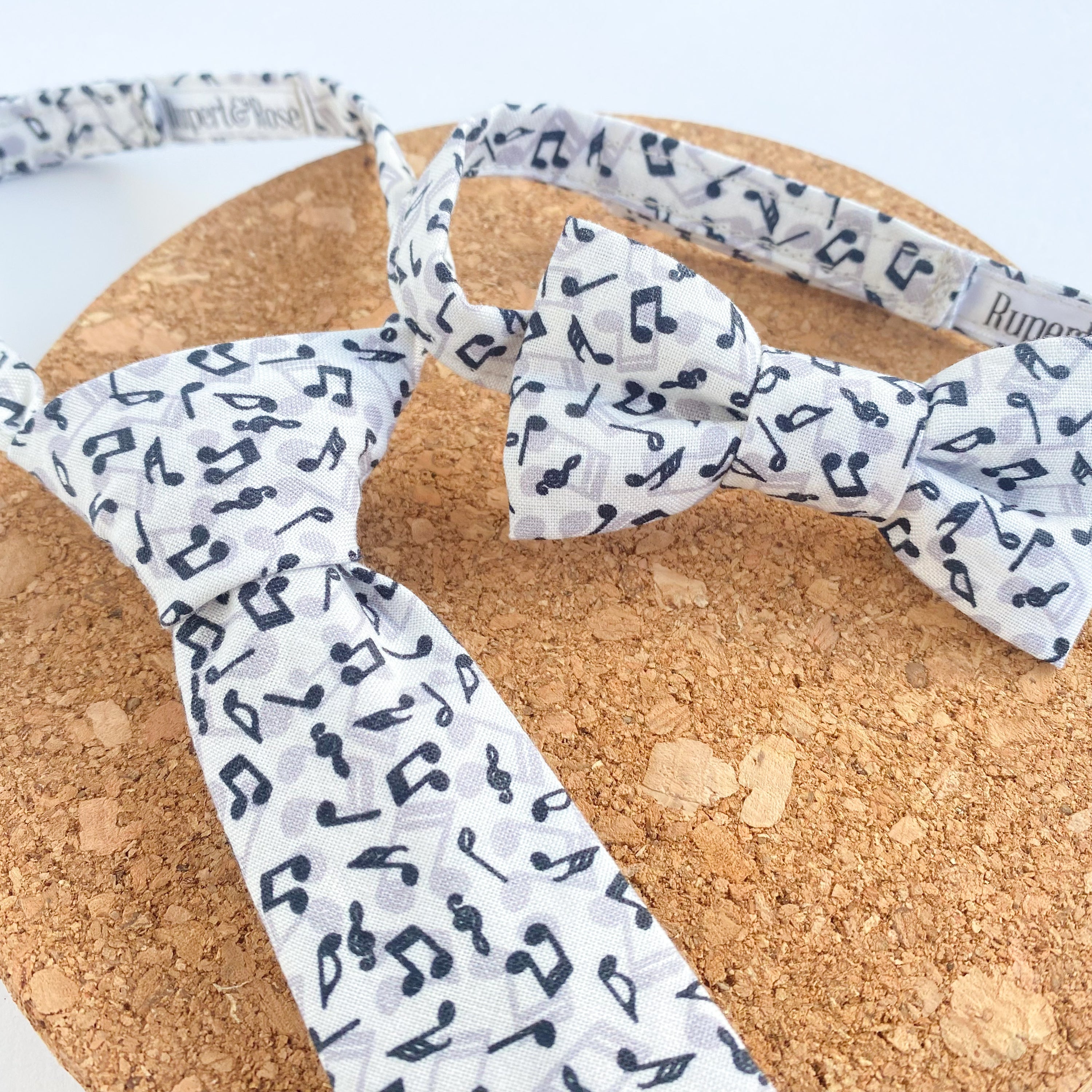 JONNY Musical Boys Bow Tie made of soft white cotton with black musical notes, pre-tied on a matching fabric strap.