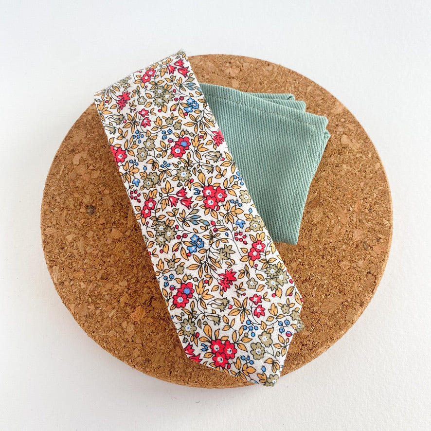 RUBEN Boys Self Tie featuring a floral pattern in sage green, cornflower blue, yellow, and vibrant pink on an off-white background.