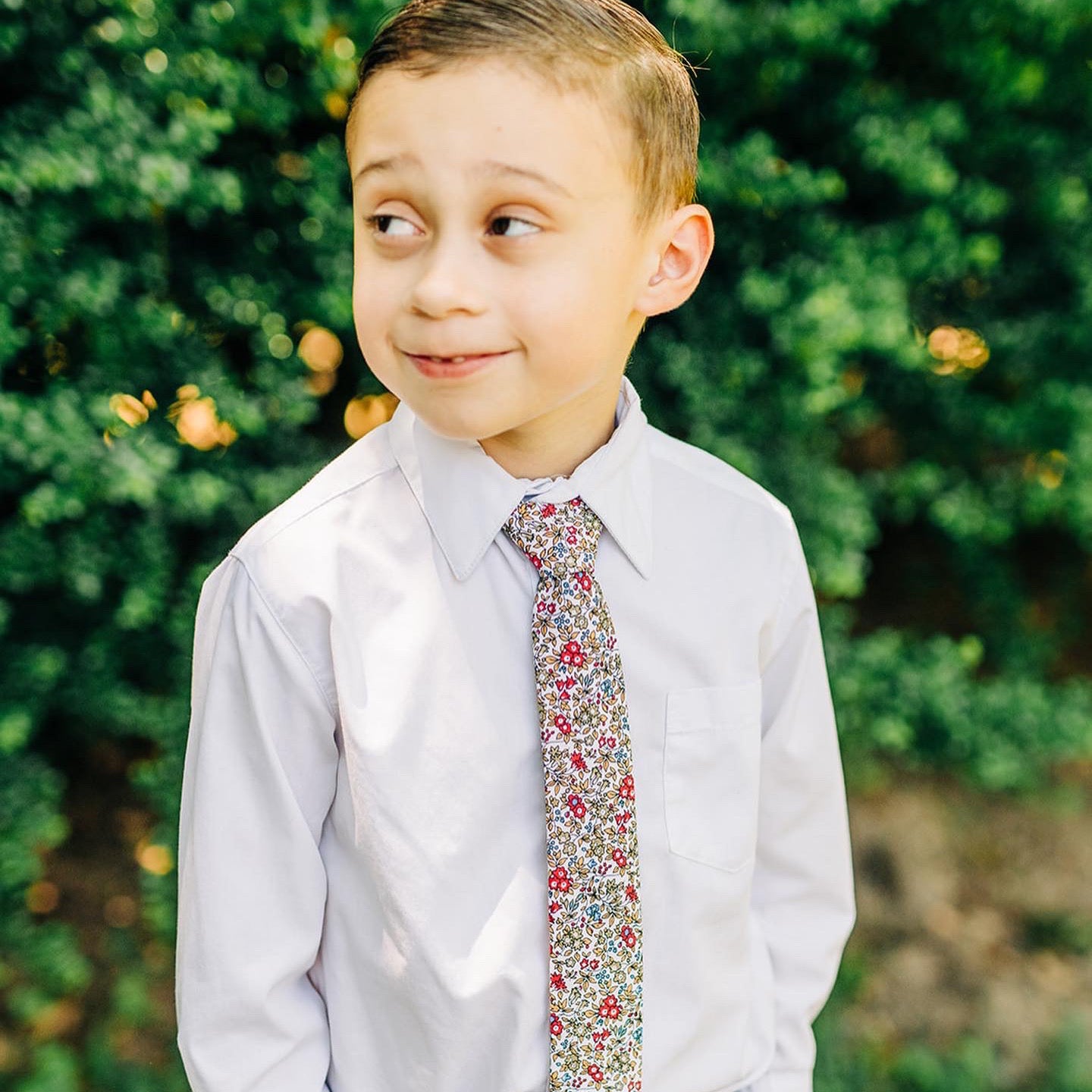 RUBEN Boys Velcro Tie featuring a floral pattern in sage green, cornflower blue, yellow, and vibrant pink on an off-white background.