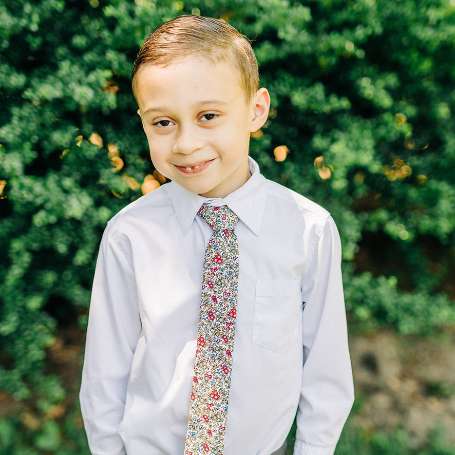 RUBEN Boys Velcro Tie featuring a floral pattern in sage green, cornflower blue, yellow, and vibrant pink on an off-white background.