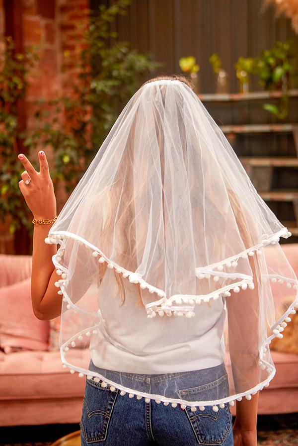 A beautiful White Pom Pom Bachelorette Party Veil featuring soft polyester fabric and playful pom-pom accents, secured with a versatile hair comb.