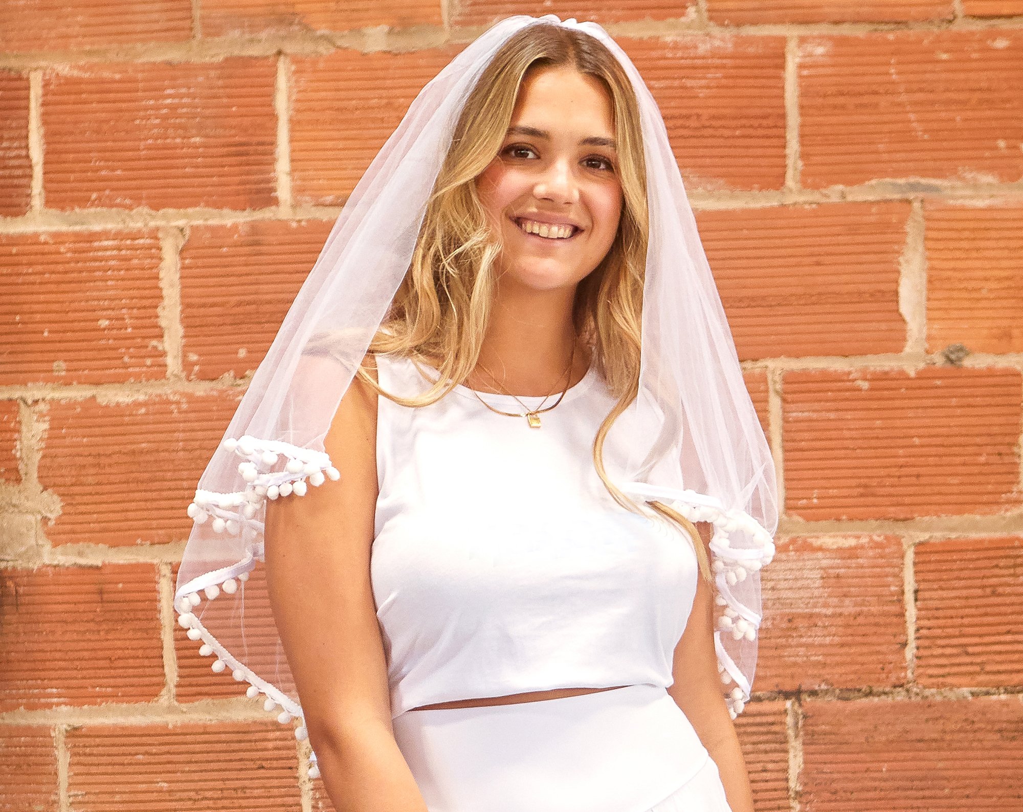 A beautiful White Pom Pom Bachelorette Party Veil featuring soft polyester fabric and playful pom-pom accents, secured with a versatile hair comb.