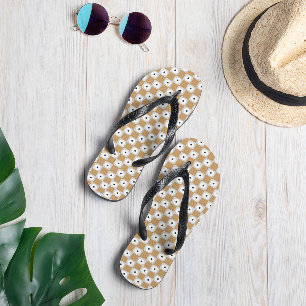 Beige and white chequered flip-flops with black rubber straps, showcasing a stylish and comfortable design for summer wear.