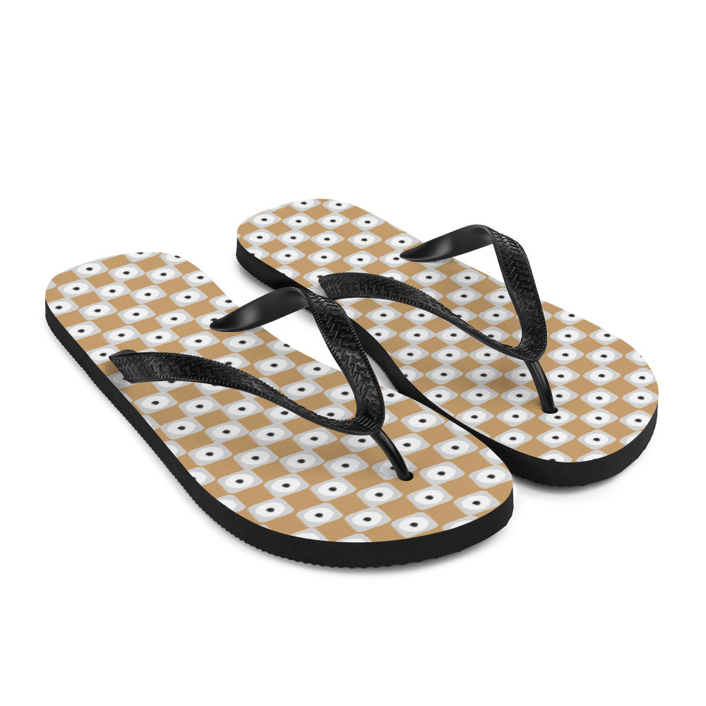 Beige and white chequered flip-flops with black rubber straps, showcasing a stylish and comfortable design for summer wear.