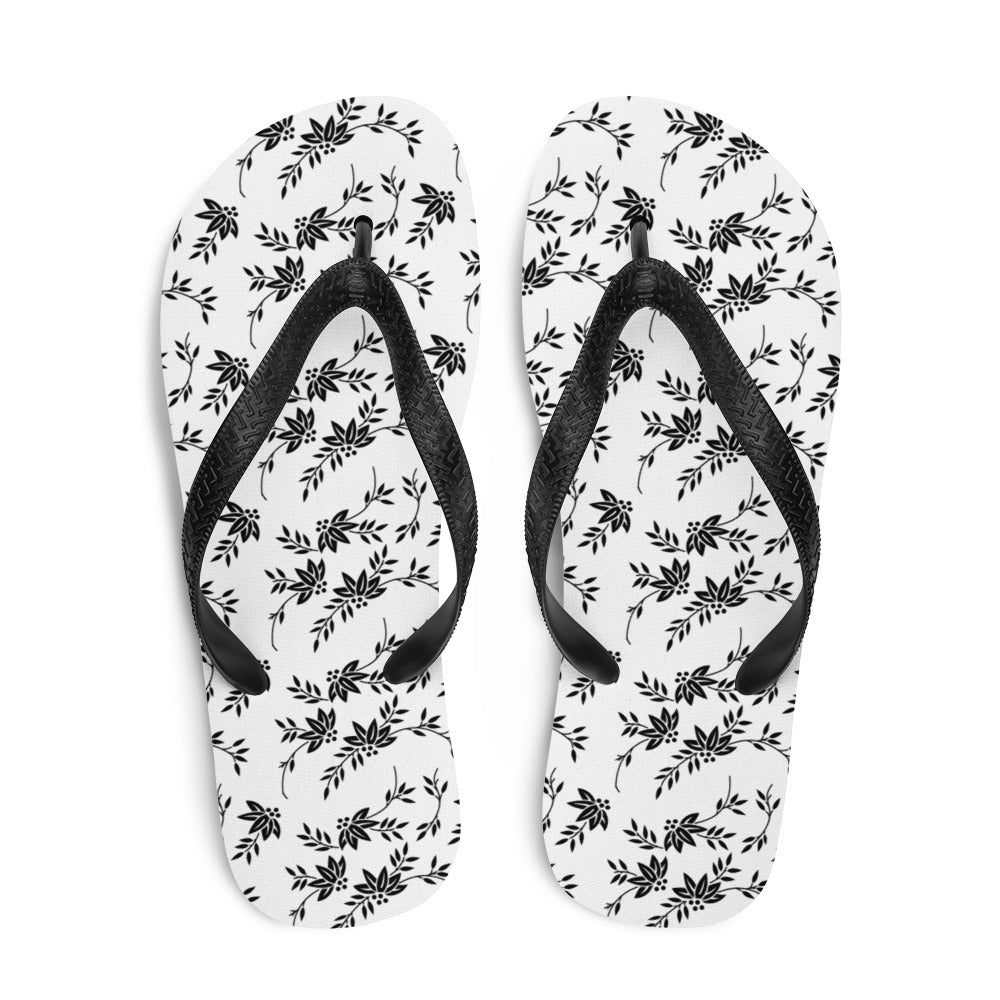 A pair of stylish Black and White Floral Flip-Flops featuring a rubber sole, soft fabric lining, and black Y-shaped straps, perfect for summer wear.