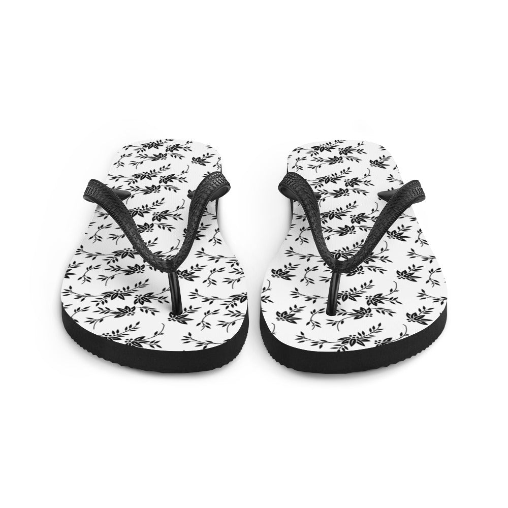 A pair of stylish Black and White Floral Flip-Flops featuring a rubber sole, soft fabric lining, and black Y-shaped straps, perfect for summer wear.