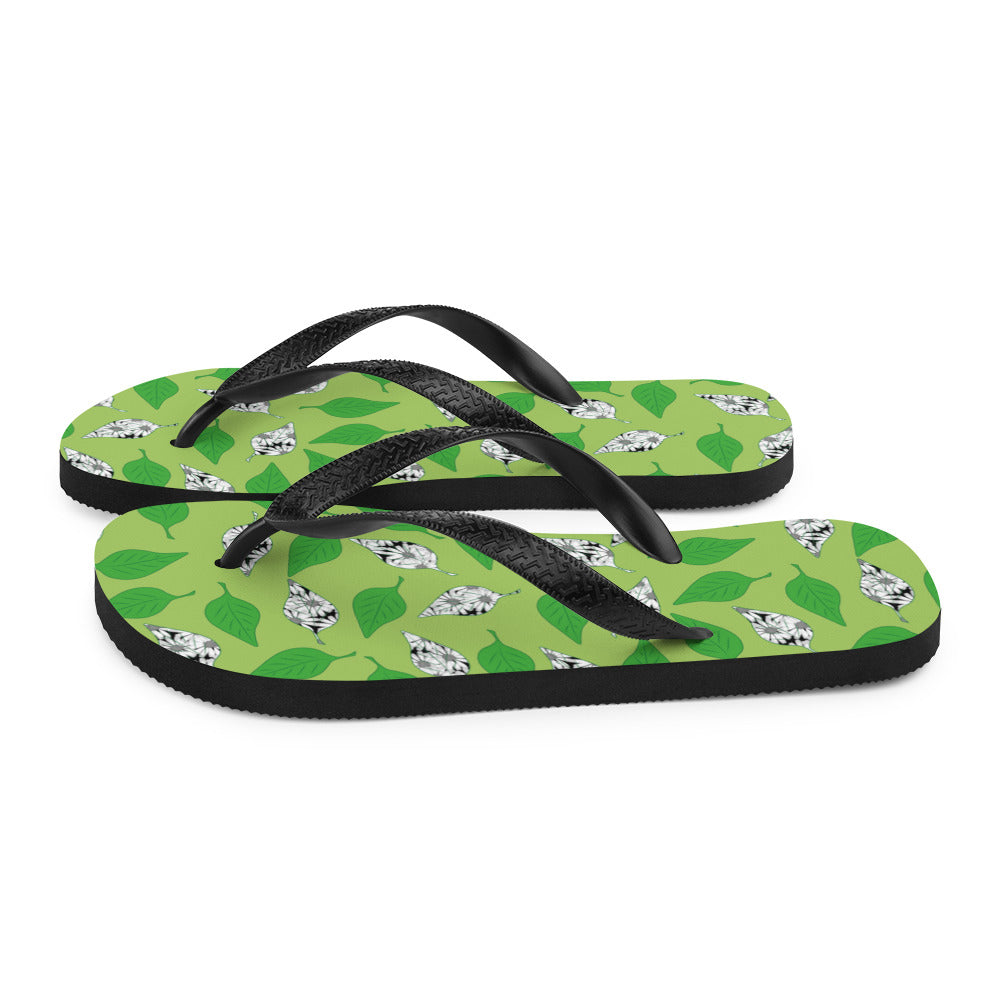 A pair of Green Leaf Print Flip-Flops featuring a vibrant leaf design, soft fabric lining, and black Y-shaped rubber straps, perfect for summer wear.