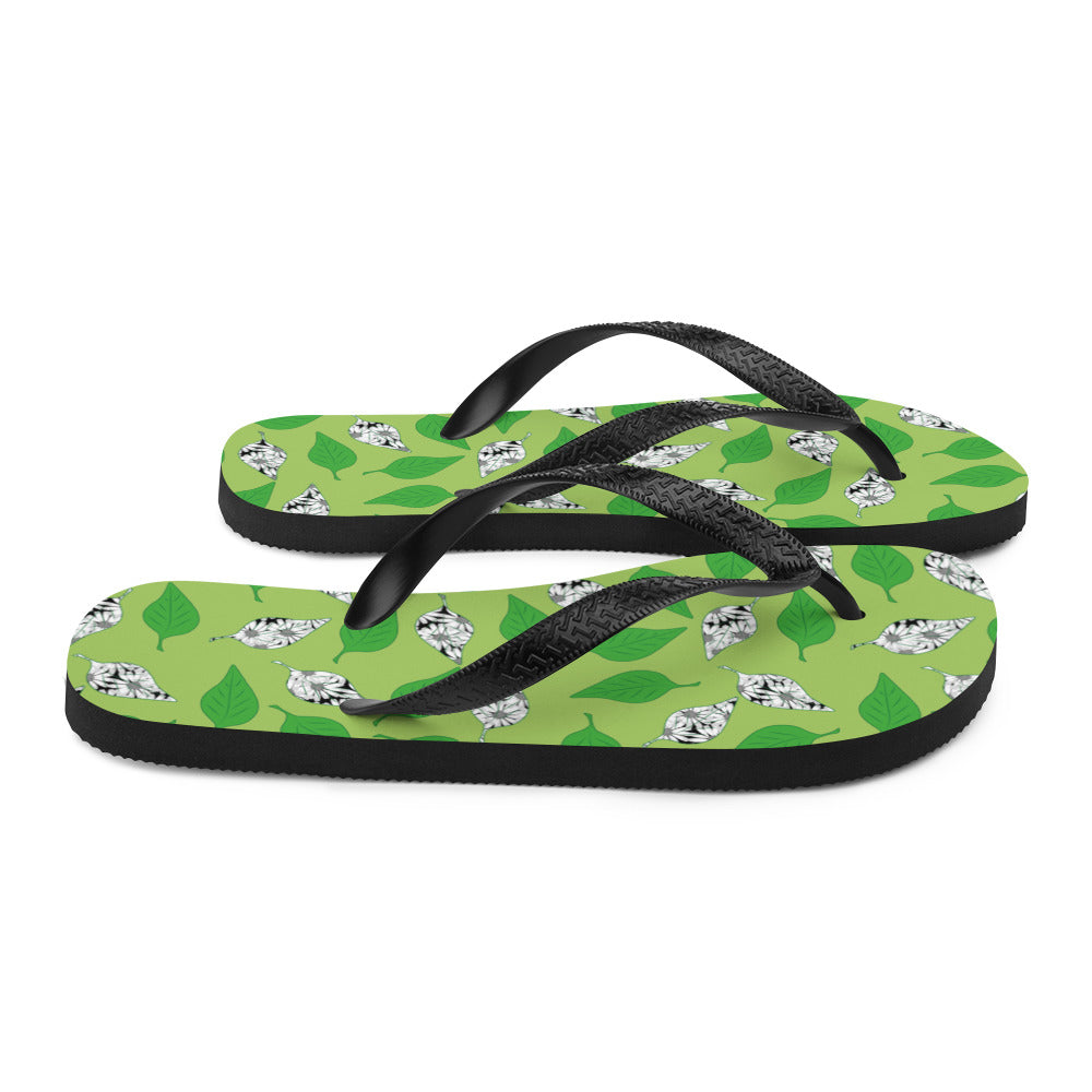 A pair of Green Leaf Print Flip-Flops featuring a vibrant leaf design, soft fabric lining, and black Y-shaped rubber straps, perfect for summer wear.