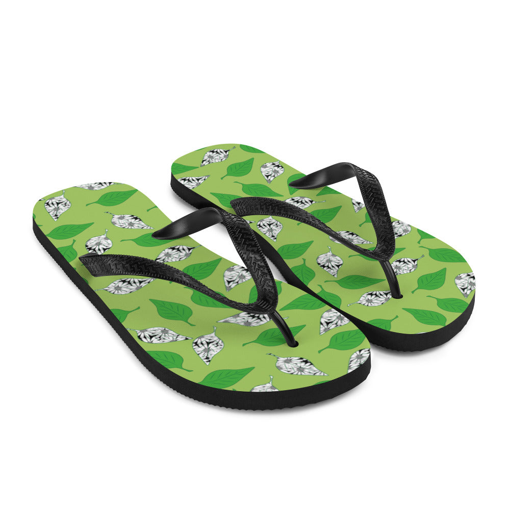 A pair of Green Leaf Print Flip-Flops featuring a vibrant leaf design, soft fabric lining, and black Y-shaped rubber straps, perfect for summer wear.