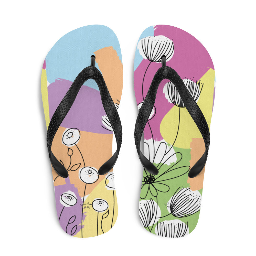 A pair of Pretty Pastel Flower Print Flip-Flops featuring a vibrant floral design, black rubber straps, and a soft fabric lining, perfect for summer wear.