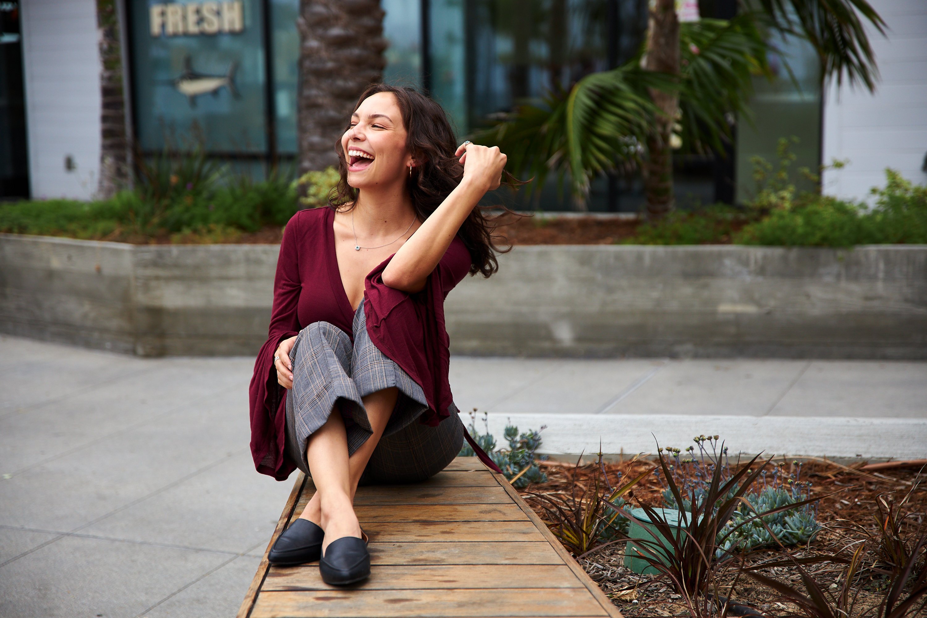 Woman laughing while sitting outdoors.