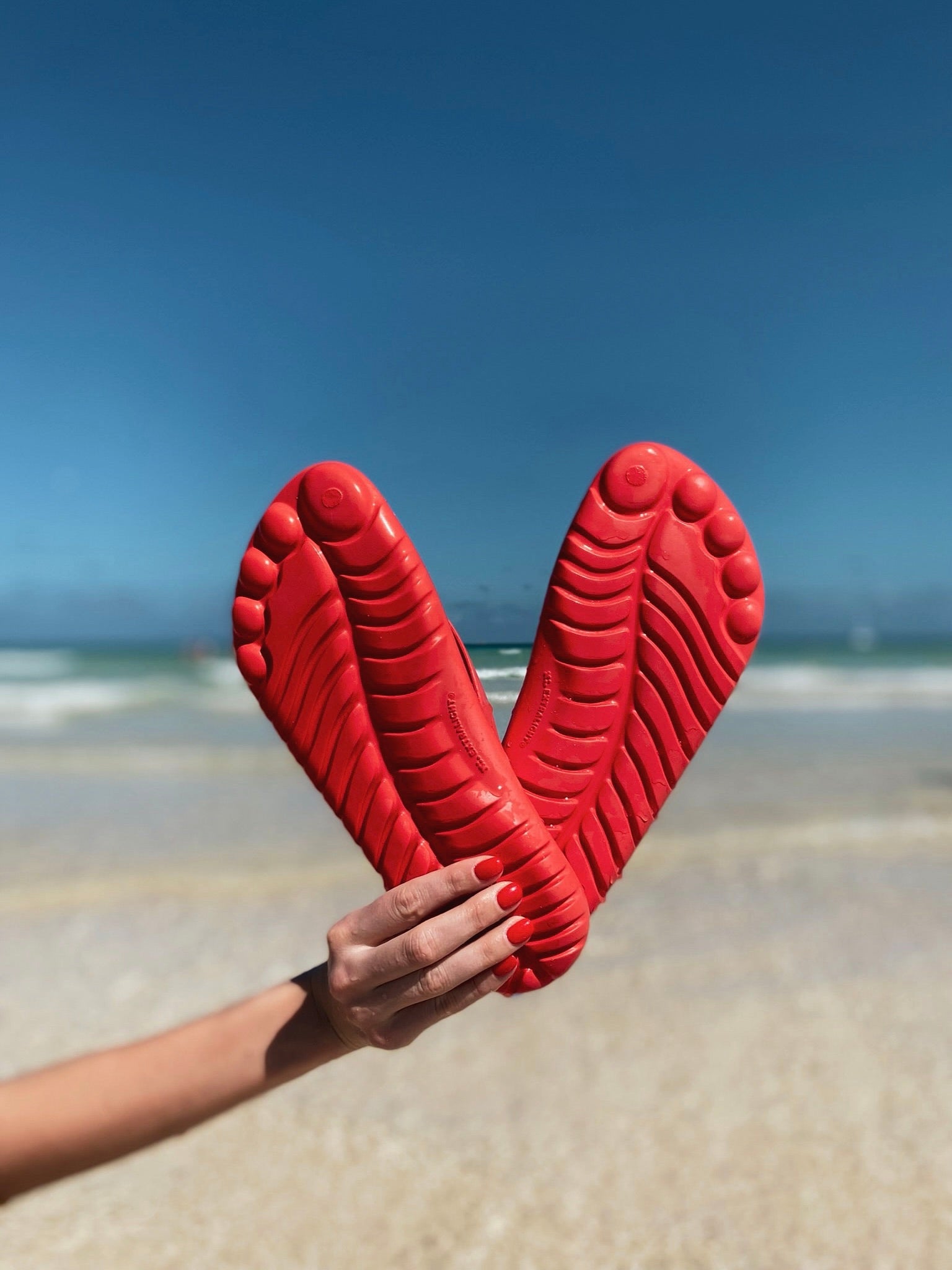 A pair of vibrant Fire Red Flip-Flops by GUDO, showcasing a minimalist design and unique sole pattern, perfect for beach and casual wear.