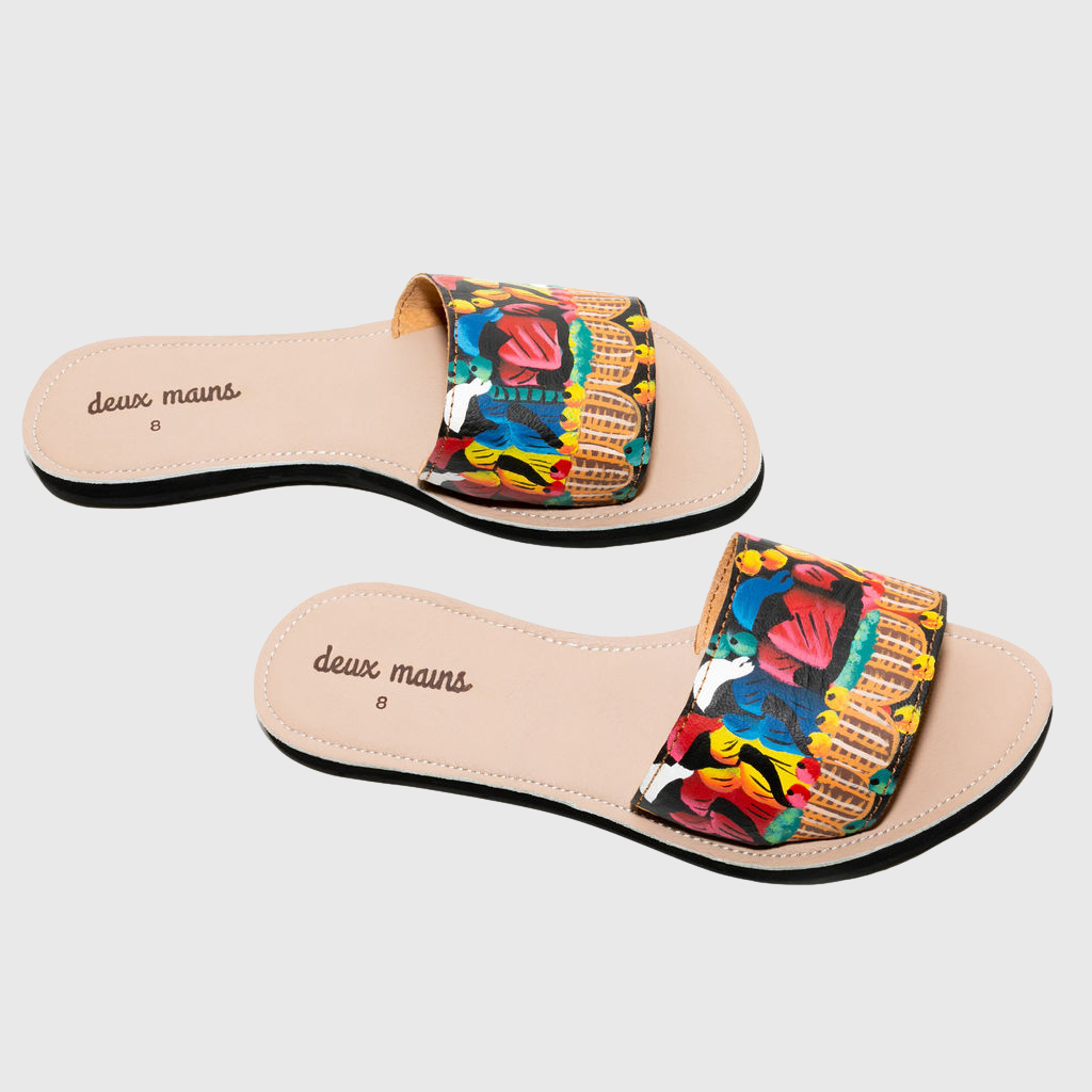 A pair of hand painted slide sandals featuring vibrant colors and unique designs, crafted from genuine leather with a repurposed tire sole.