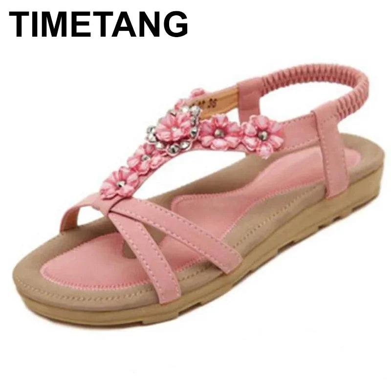 A pair of stylish pink flower sandals for women, featuring a flat heel and adjustable ankle strap, perfect for casual wear.