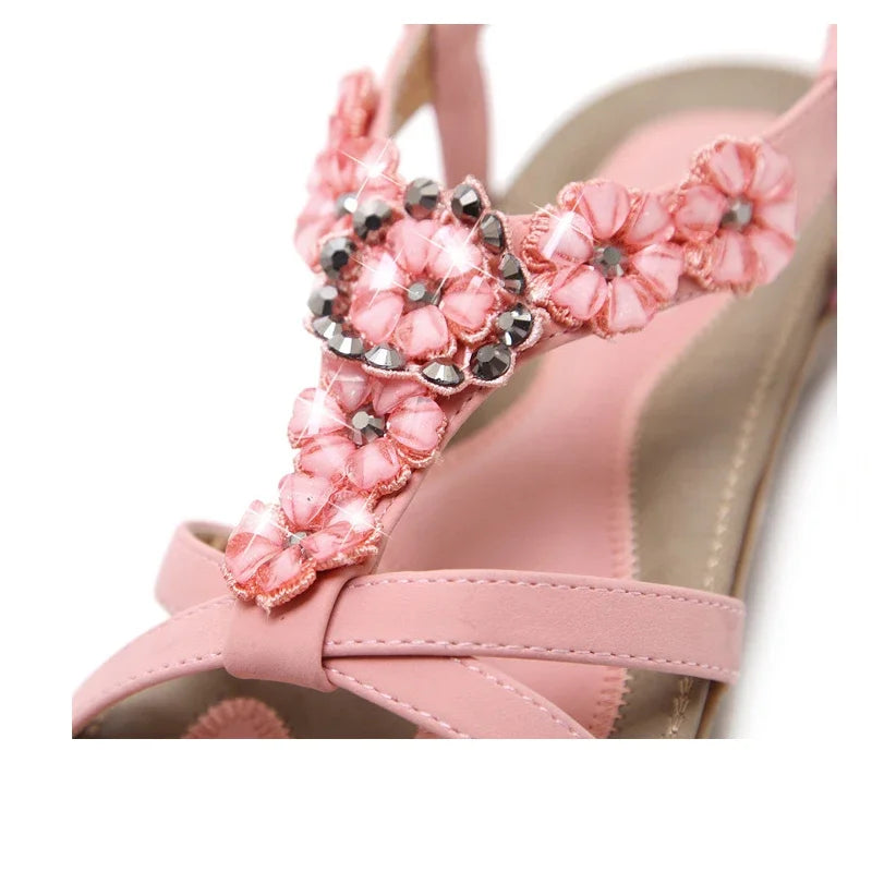 A pair of stylish pink flower sandals for women, featuring a flat heel and adjustable ankle strap, perfect for casual wear.