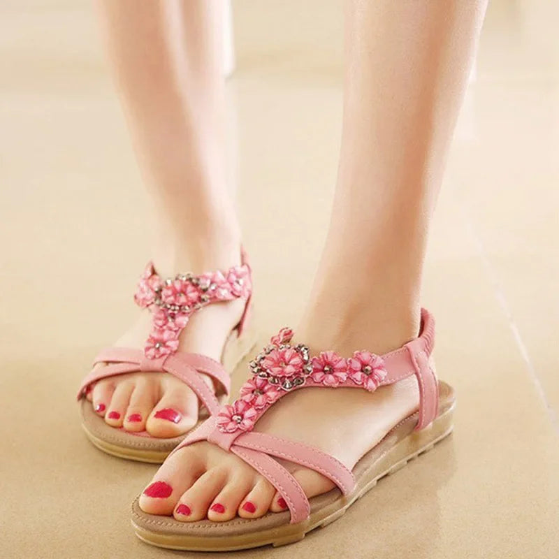 A pair of stylish pink flower sandals for women, featuring a flat heel and adjustable ankle strap, perfect for casual wear.