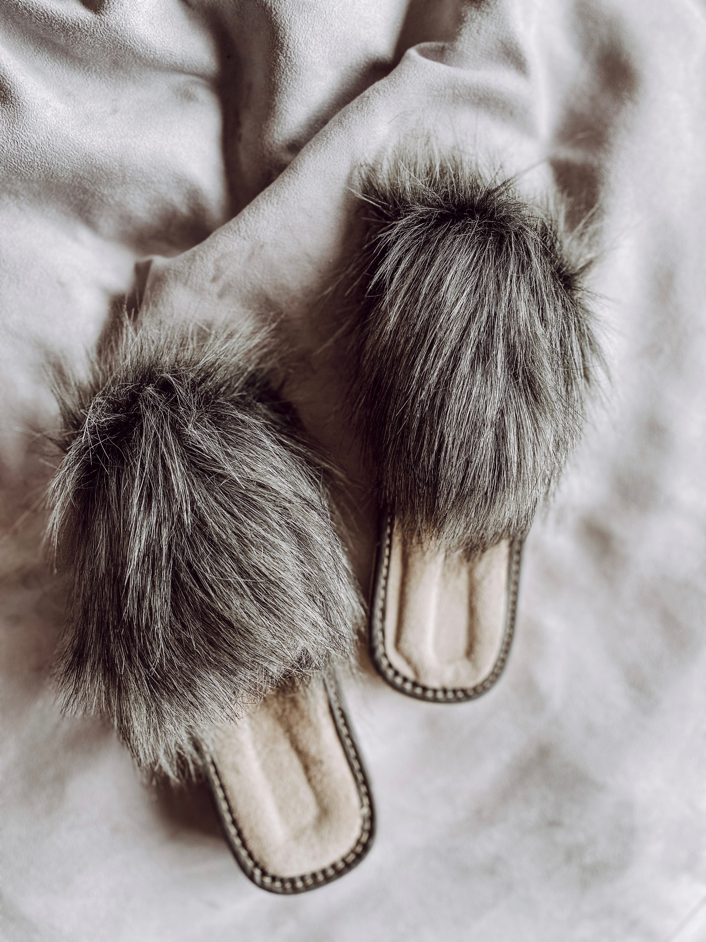 Cozy faux fur grey slippers with a cushioned insole and foam bottom, perfect for home wear.